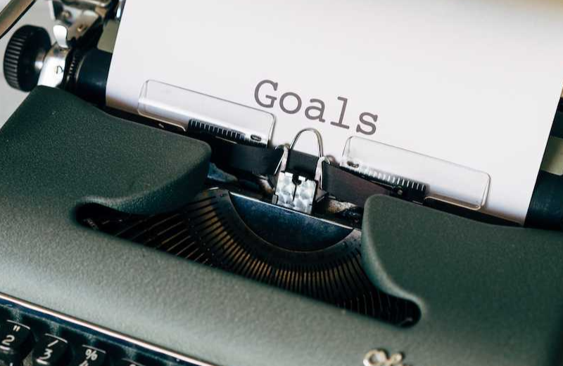 A dark green Olympia typewriter with a piece of paper that has had the word 'Goals' printed on it