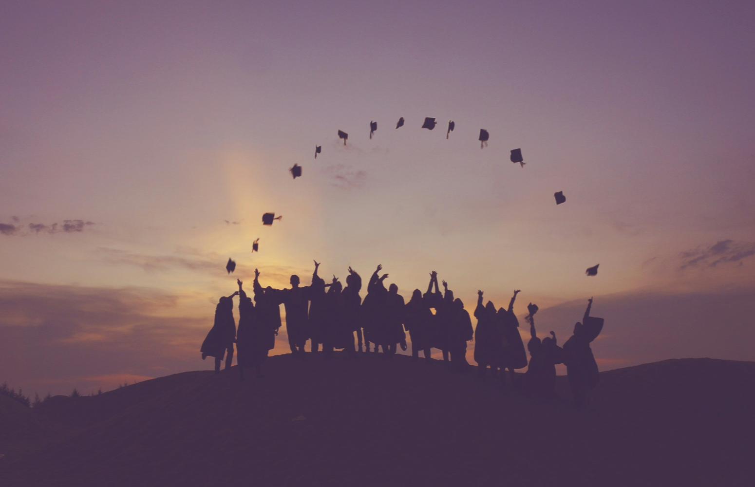 As group of graduates celebrating their achievement at sunset